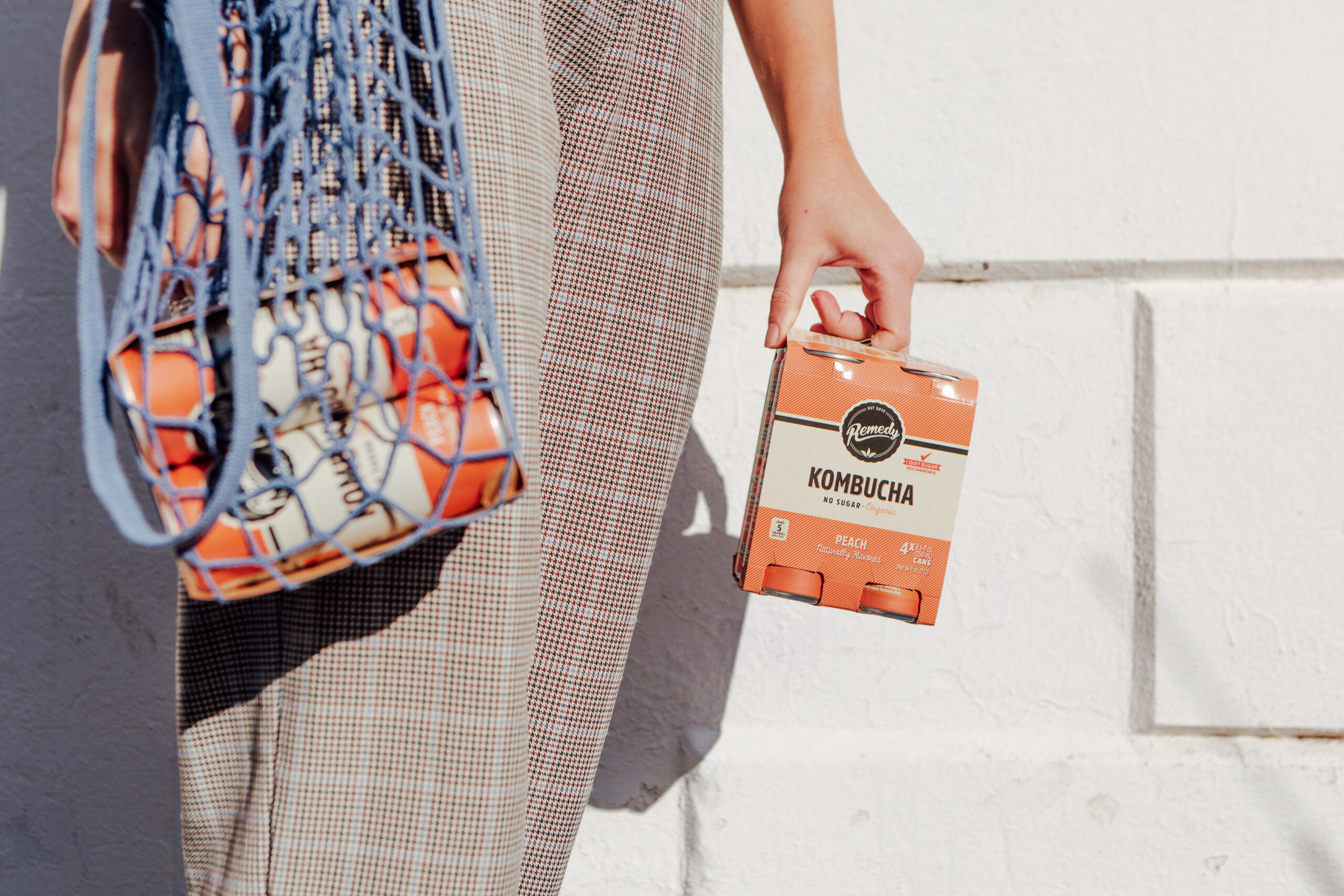 Person with re-usable shopping bag and Peach Remedy Kombucha